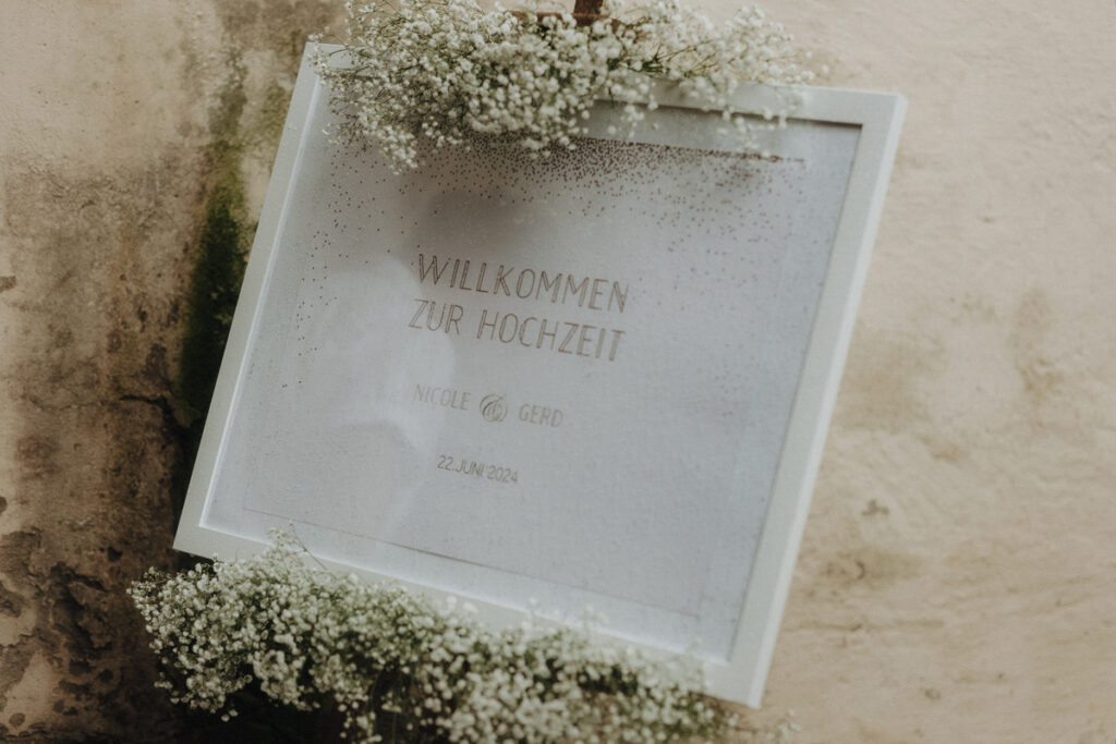 Welcome Sign in white and gold with floral arrangement