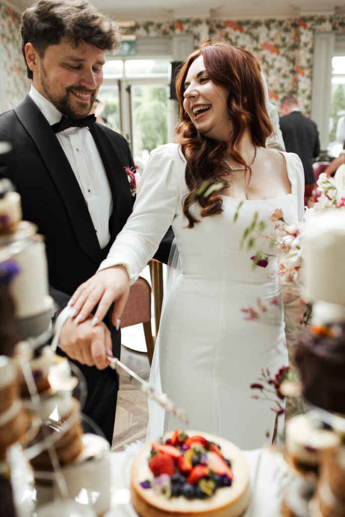 Braut und Bräutigam schneiden Hochzeitstorte an