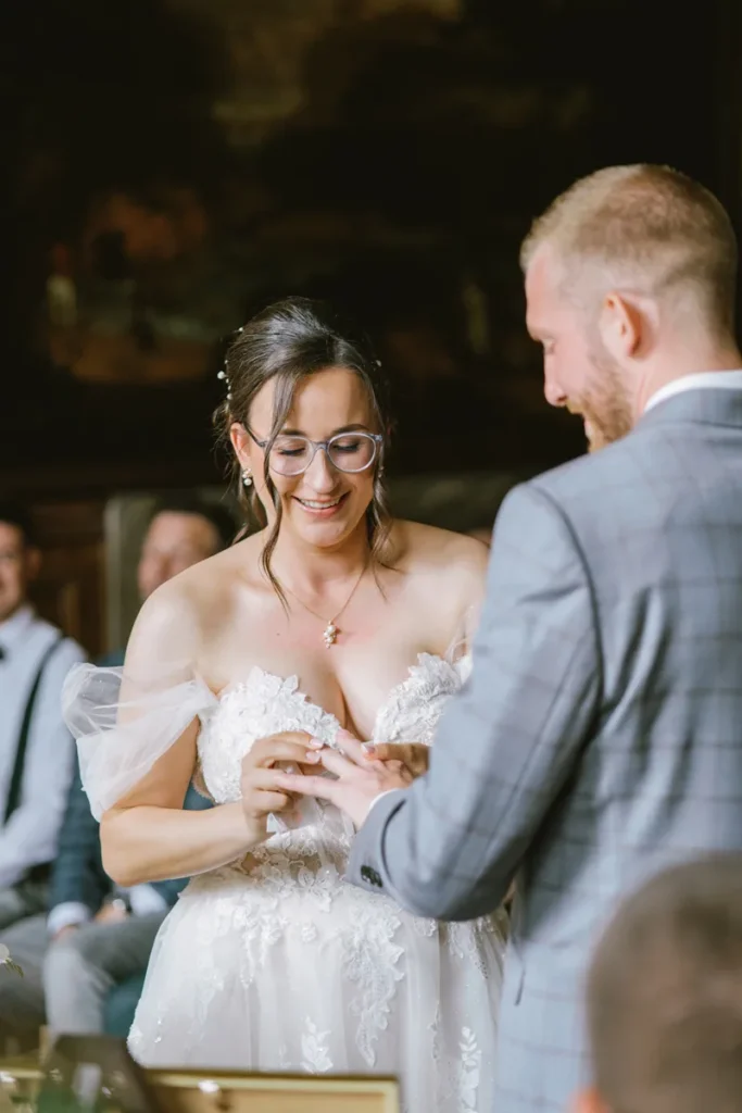 Smiling bride placing the wedding ring onto the groom's finger during the ceremony