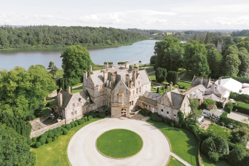Aerial drone shot of Castle Leslie Estate facade with the tranquil lake in the background