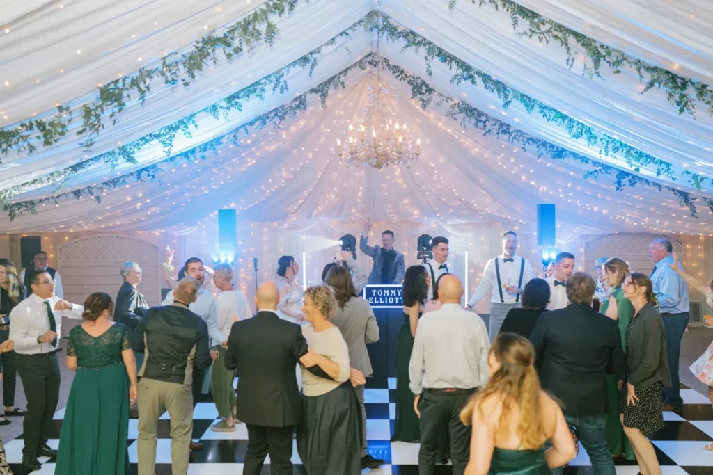 Volle Tanzfläche mit feiernden Hochzeitsgästen und DJ Tommy Elliott im Hintergrund
